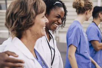 Female nurses laughing with arms around each other