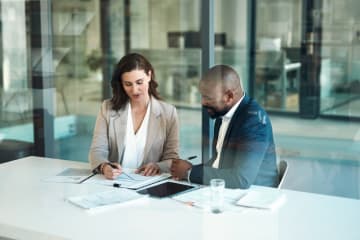 man and women sitting in office going over paperwork and finances