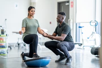 Male Physical therapist assisting a female patient.