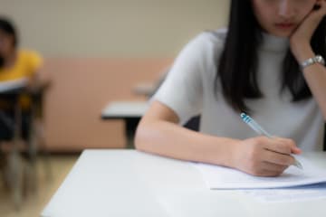  School student's taking exam writing answer in classroom for education and literacy concept - stock photo