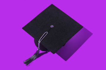 Black graduation cap with silver tassel, in a row, on a purple background. Graduation, achievement, goal, degree, master's degree, bachelor's degree, university, college and success concept. - stock photo