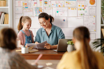 Elementary teacher talking with student at desk