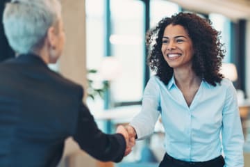 business women smiling while shaking hands after earning degree from GCU