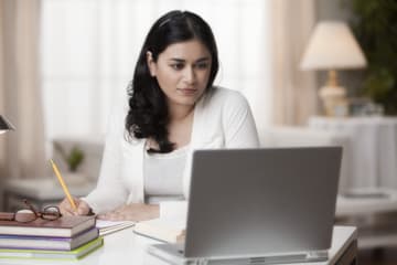 woman studying on laptop and taking notes