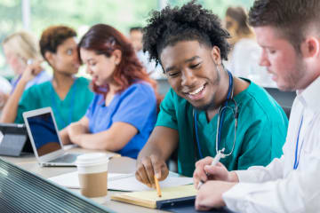 Diverse male medical students work together on project.