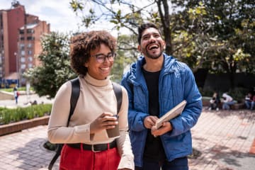 Two friends laugh together on college campus.