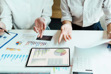 Two people discussing economics while looking over charts and graphs