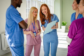Several nurses standing around discussing a patient's chart.