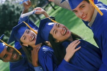 Group of students smiling in their blue cap and gown at graduation