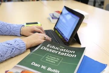 student taking notes from their dissertation textbook