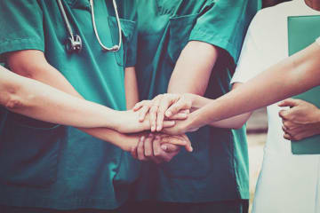 a group of nurses putting their hands together for a cheer