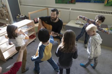 Man playing guitar with little kids around him