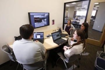 Group of people gathered around with laptops