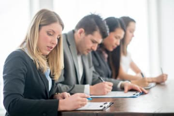 four people sitting at a table signing paperwork