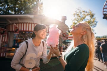 two girls at a carnival eating cotton candy