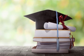 A grad cap on top of a stack of books