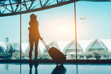 Female student watching a plane take off in an airplane terminal