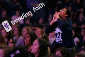 Female student worshiping during Chapel with hashtag trending faith