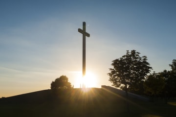cross on a hill in front of the sun rising
