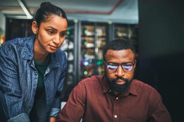 Two systems engineers work with computers