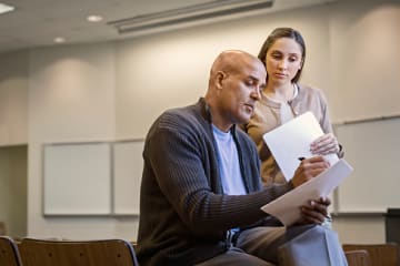 student and professor speaking and reviewing papers
