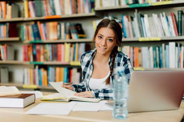 female student studying for college exams in library