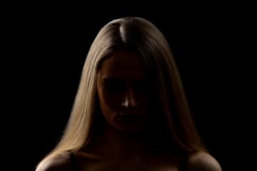 person standing in a dark area with light on one side of their face