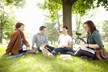 Students studying in grass at park