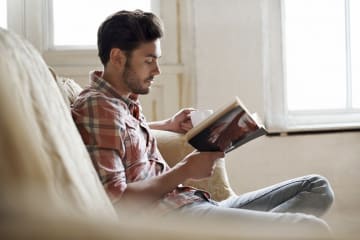 Man reading with a drink on a couch