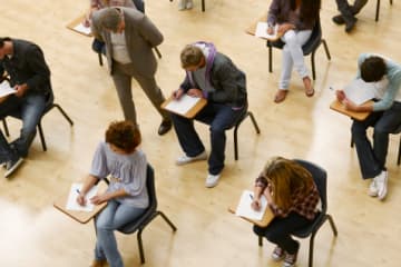 Teacher watching several students taking test in auditorium