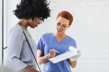 Acute nurse practitioner helping patient with paper in hospital