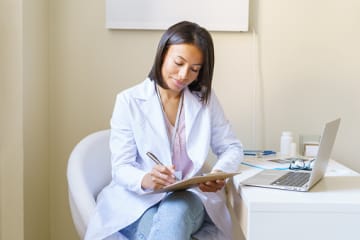 An Advanced Practice Registered Nurse taking notes on a clipboard