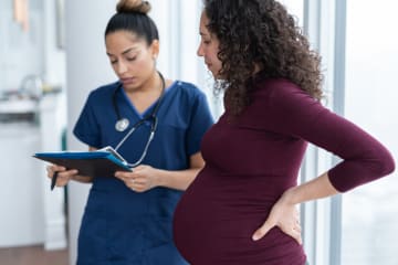 A nurse midwife consulting with a pregnant patient