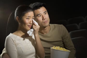 Couple watching movie in theatre that is making them cry