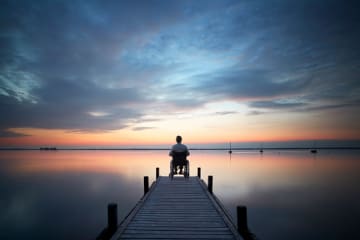 Man looking out at the sunset from dock