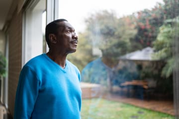 man standing at window having hope in hard times