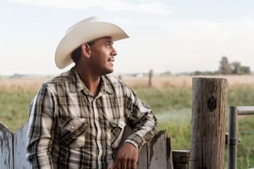 Man standing next to fence looking at field