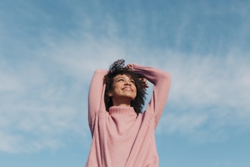 Woman smiles and looks up at the blue sky