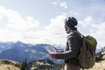 Strong and courageous hiker looking for path on map