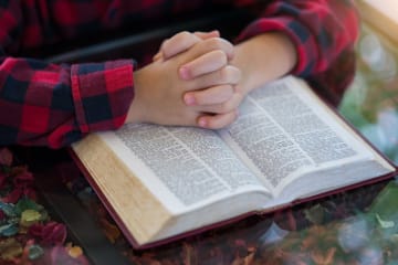 hands held together on top of a bible
