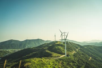 Wind mills on mountain range with overcast sky