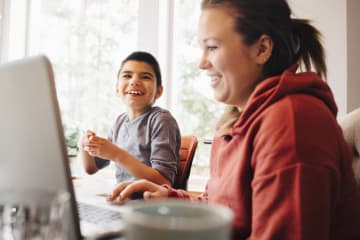 a student working on schoolwork at home with his mother