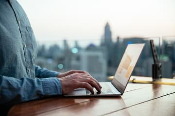 A doctoral student typing on computer by a window