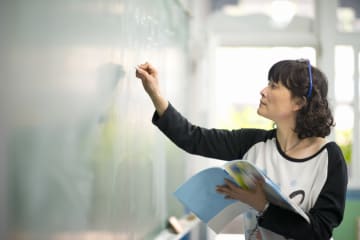 teacher writing on a chalkboard in the classroom