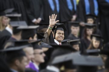 college student waving at graduation