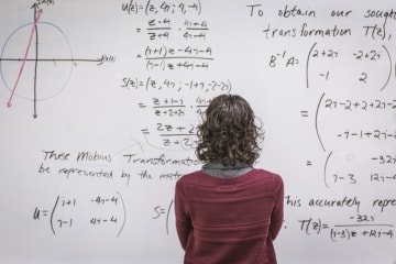 math teacher facing the board in reflection