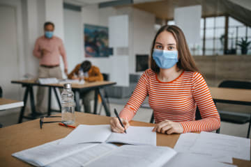 Girl in a mask working on homework