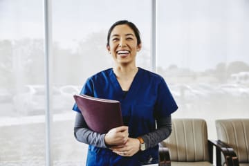 Nurse smiling and holding paperwork in office