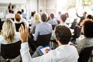 student raising hand in professional setting