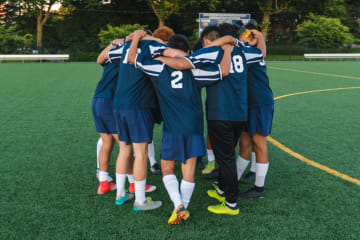 college soccer players having a team huddle before game